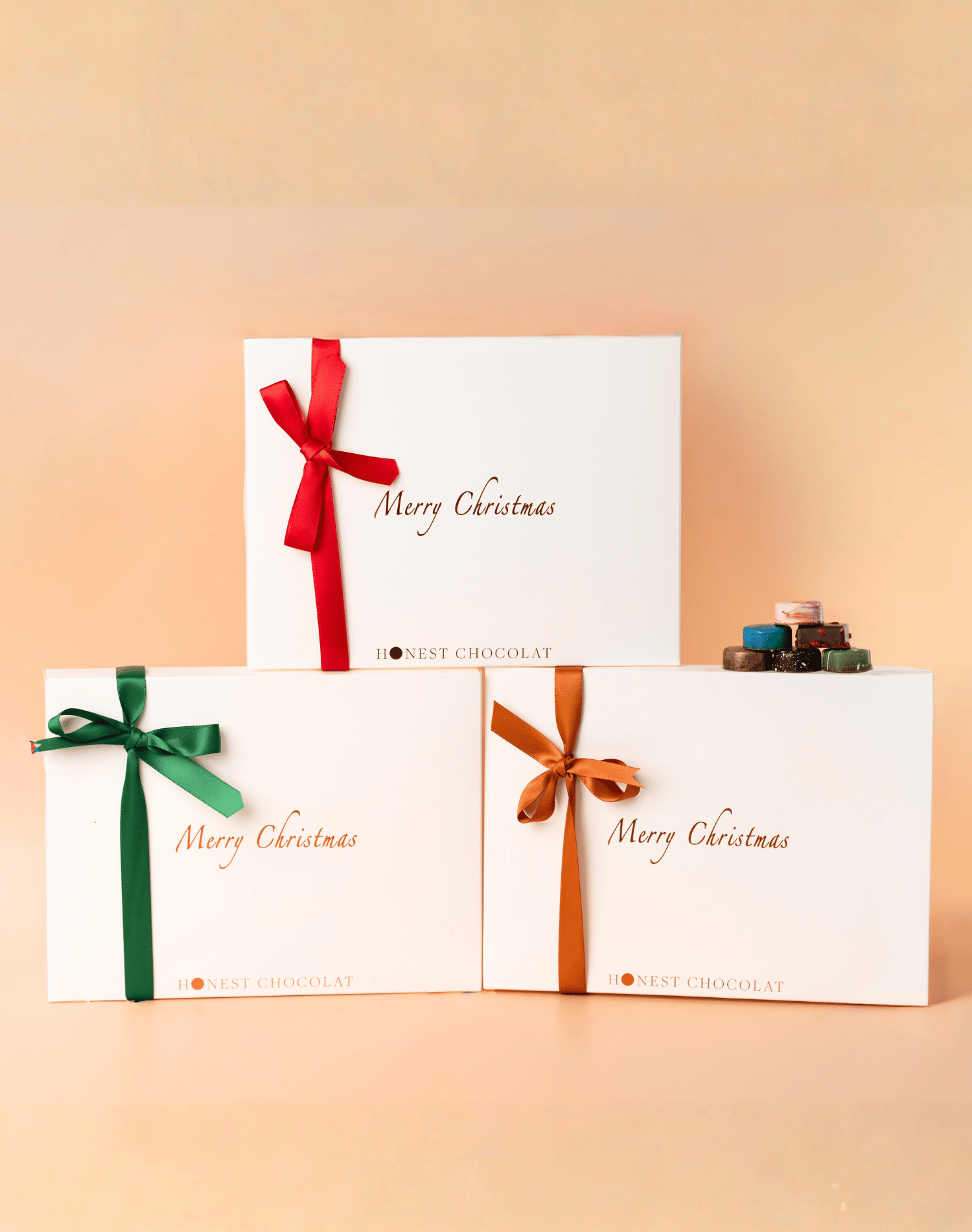 Set of Christmas-themed chocolate boxes with ribbons on a beige background