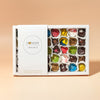 A box of assorted chocolate bonbons from Honest Chocolat, with each bonbon uniquely shaped and colored, displayed in a well-packaged and arranged box