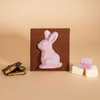 Chocolate bar with a pink rabbit mold on a beige background