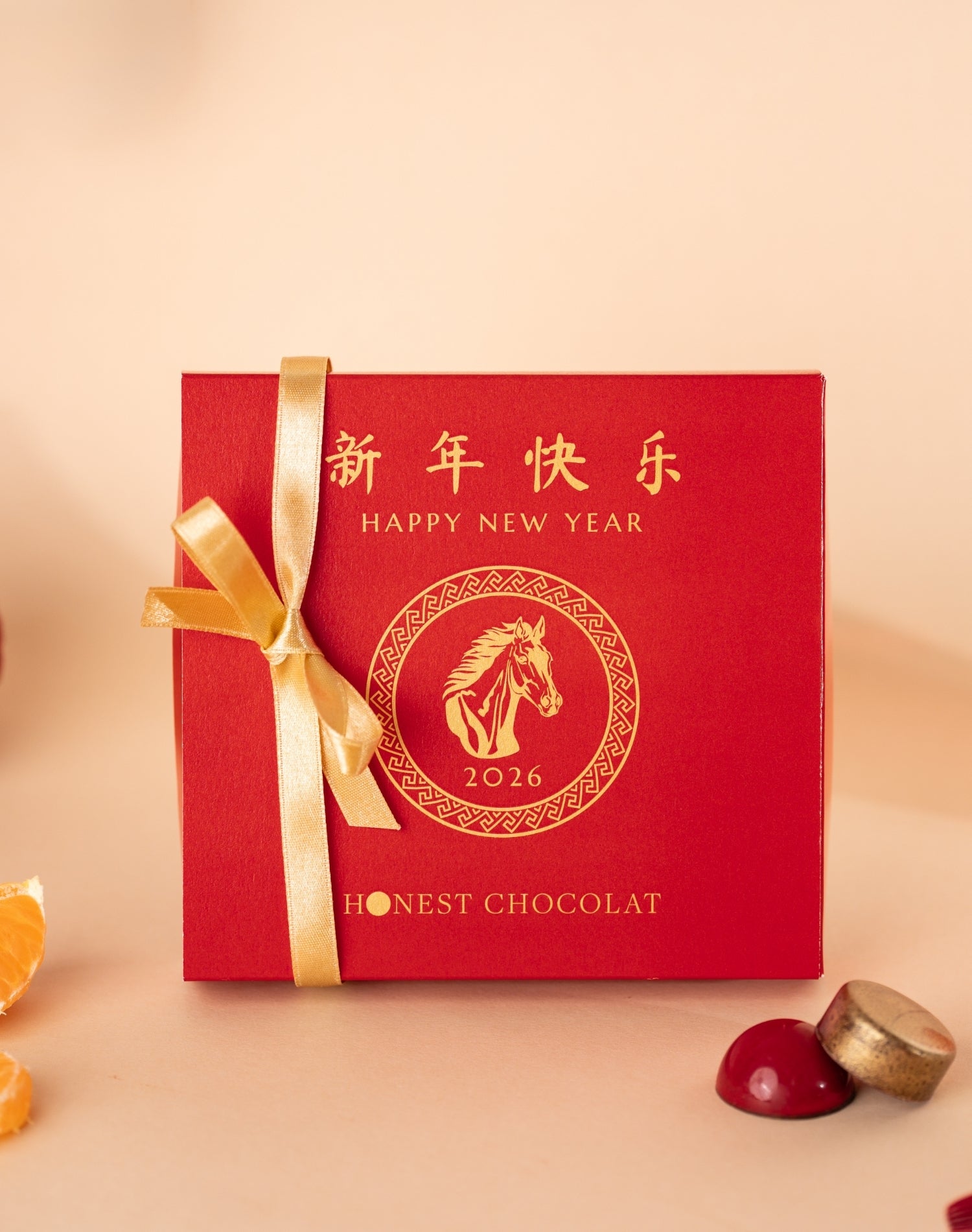 Chinese New Year red chocolate box with gold ribbon and 'Happy New Year 2026' design on a light background