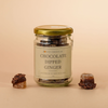 Jar of chocolate-dipped ginger with two pieces on a beige background