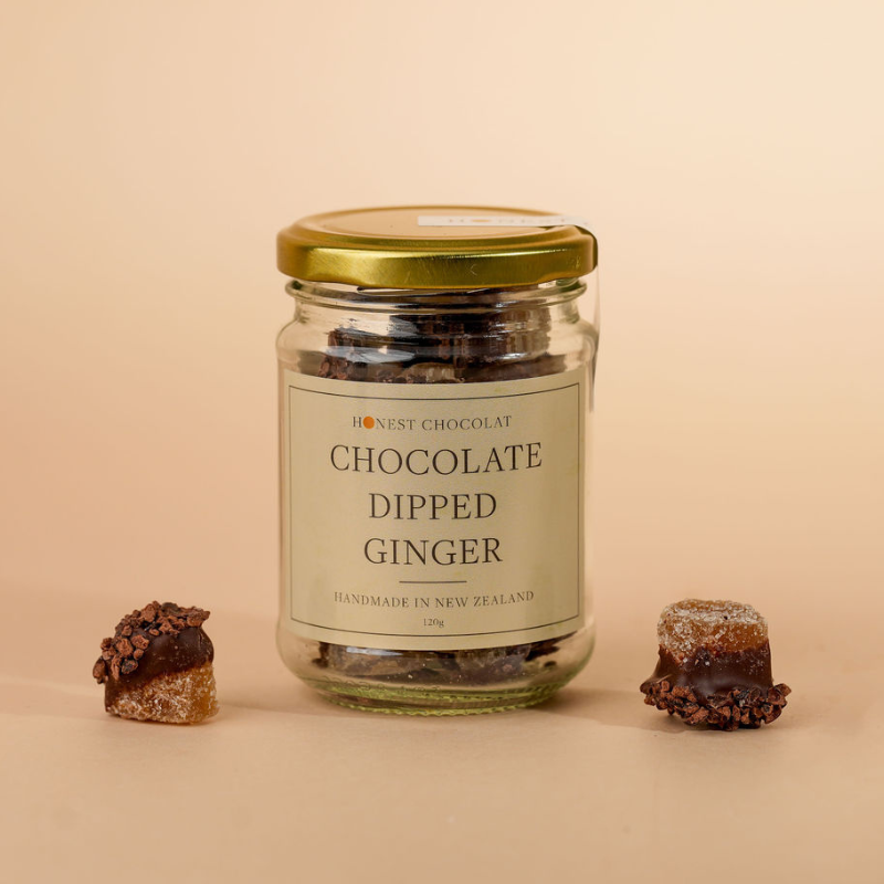 Jar of chocolate-dipped ginger with two pieces on a beige background