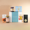 Honest Chocolat chocolate lovers gift box with a chocolate bar, hokey pokey jar, bonbon box, lollipop, and salted caramel spread jar, on a warm beige background
