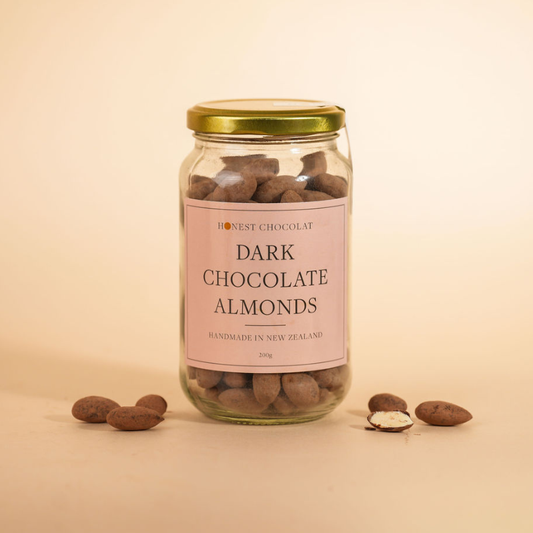 Jar of dark chocolate almonds with a pink label on a beige background
