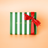Green and white striped gift box with a red ribbon on a beige background