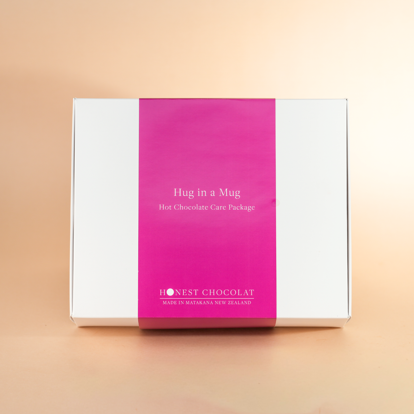 Hug in a Mug hot chocolate care package box with pink and white design on a beige background