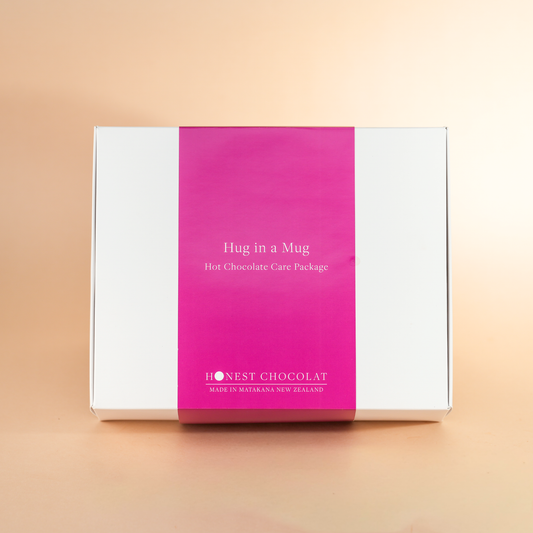 Hug in a Mug hot chocolate care package box with pink and white design on a beige background