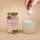 Jar of marshmallows selection with a hand holding a marshmallow over a ceramic cup on a beige background