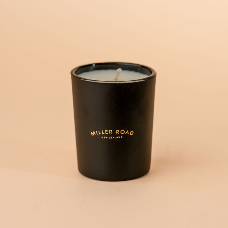 Black candle with 'Miller Road New Zealand' text on a beige background