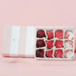 Box of assorted red and white bonbon chocolates on a pink background