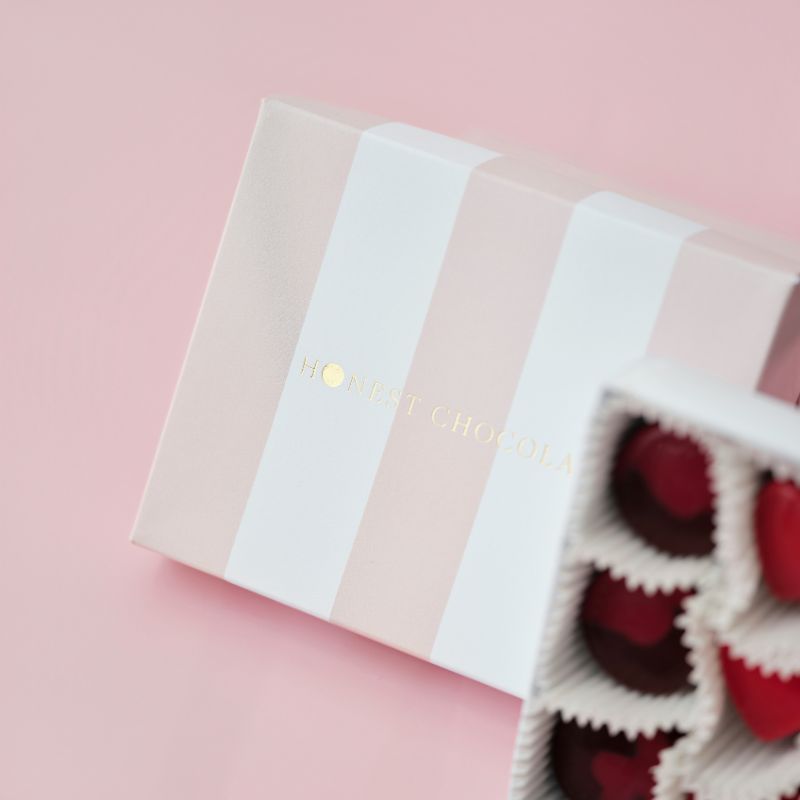 Open box of chocolates with a pink background