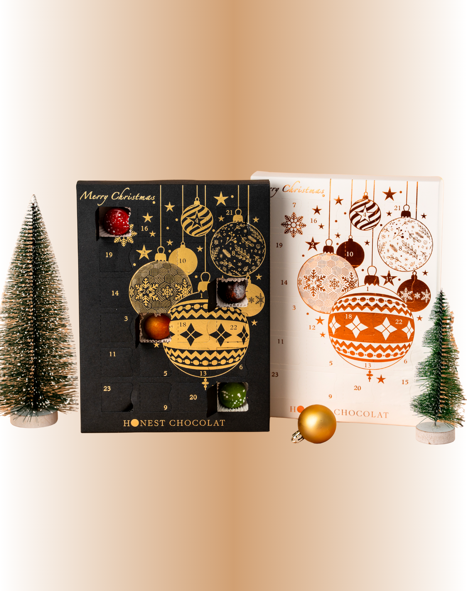 Luxury Christmas Chocolate Advent Calendars by Honest Chocolat in black & gold and white & bronze designs, displayed with festive decorative trees and ornaments, handcrafted in New Zealand.