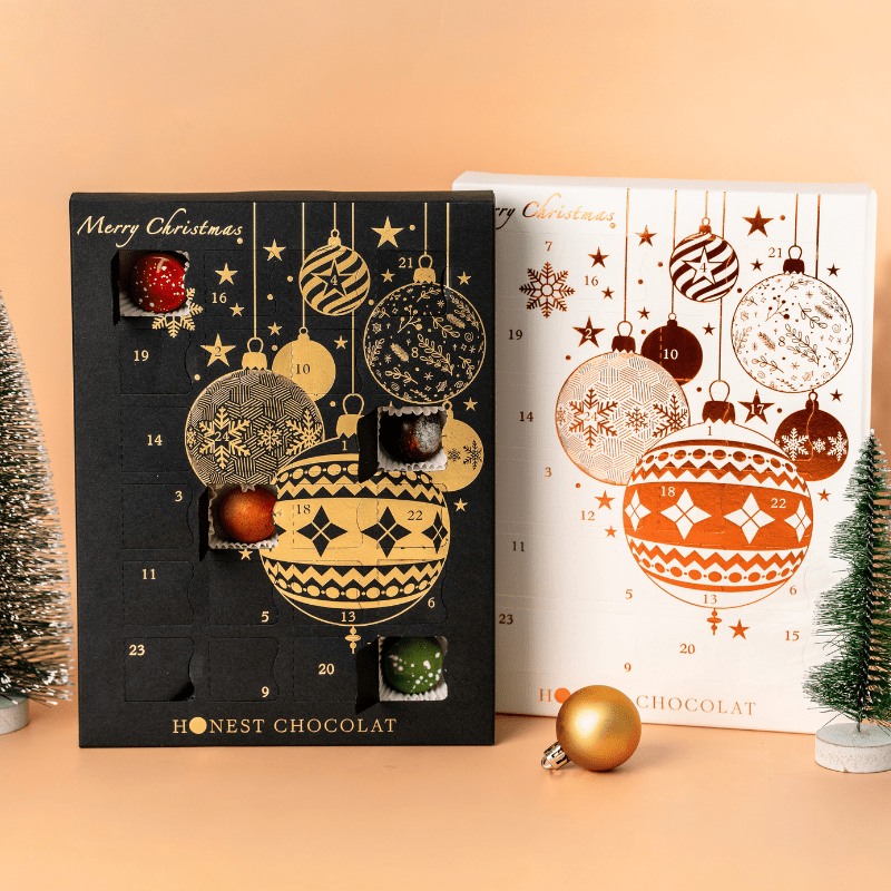 Collector’s pair of luxury Christmas Chocolate Advent Calendars by Honest Chocolat in black and gold and white and bronze, each filled with 24 handcrafted chocolates.