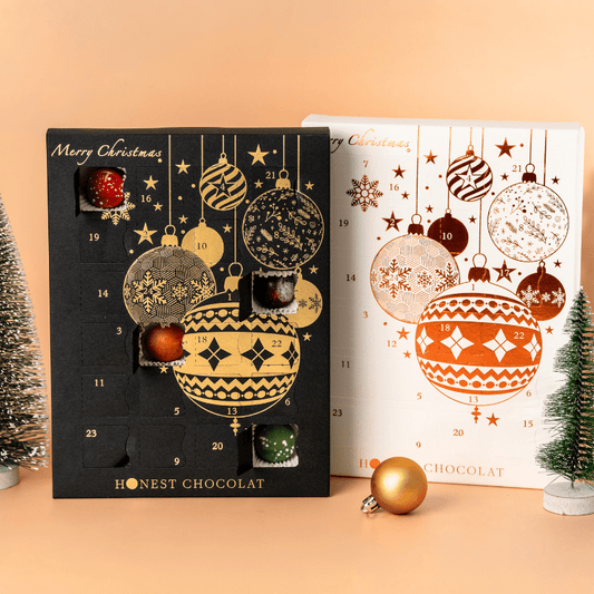 Collector’s pair of luxury Christmas Chocolate Advent Calendars by Honest Chocolat in black and gold and white and bronze, each filled with 24 handcrafted chocolates.
